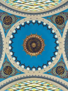 Looking up into a bright blue mosque dome ringed with small windows