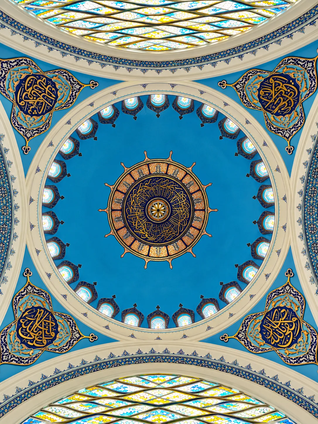 Looking up into a bright blue mosque dome ringed with small windows