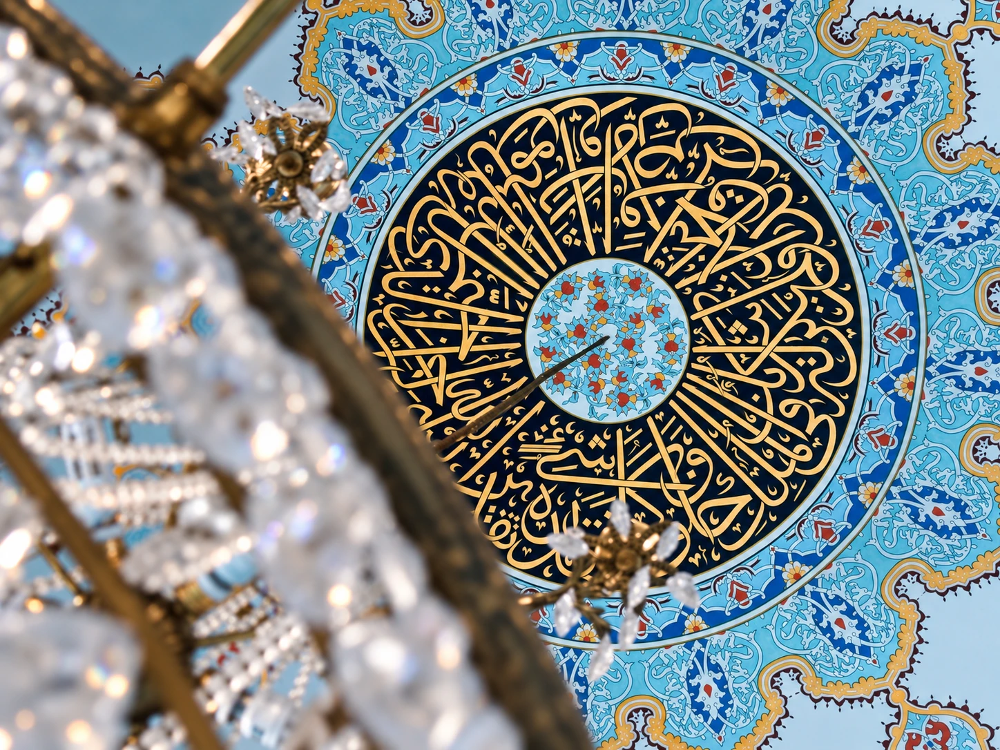 Turquoise and gold ceiling medallion seen past a crystal chandelier